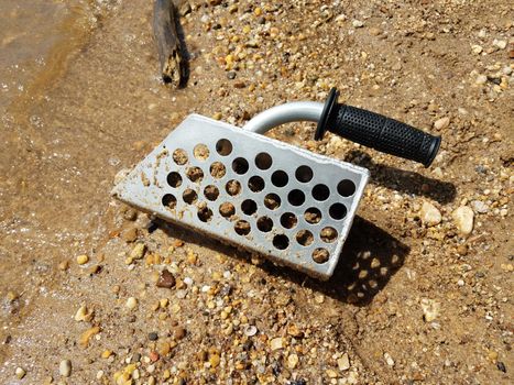 metal scooper on beach with sand and rocks