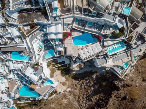 Drone view over Santorini, aerial view over the whitewashed village of Oia with luxury vacation resort with infinity pools in Santorini Greece