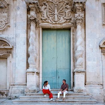 couple men and woman on citytrip Ortigia in Syracuse in the Morning. Travel Photography from Syracuse, Italy on the island of Sicily. Cathedral Plaza and market with people whear face protection during the 2020 pandemic