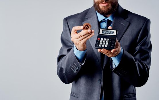 Businessman with calculator in hands and cryptocurrency Bitcoin wealth exchange rate