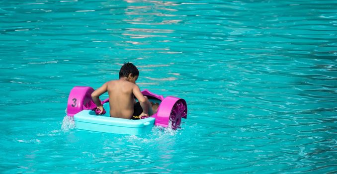 Child playing a water pedal boat in a swimming pool