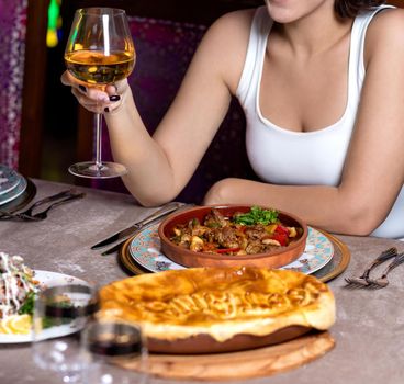 Woman drinking white wine with meat meal at the restaurant