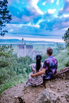couple men and woman visit Neuschwanstein Castle. Beautiful view of world-famous Neuschwanstein Castle, the nineteenth-century Romanesque Revival palace built for King Ludwig II on a rugged cliff near Fussen, southwest Bavaria, Germany