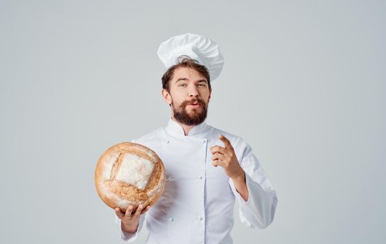 An emotional chef in light clothes and a headdress with a loaf of bread in his hand