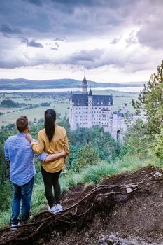 couple men and woman visit Neuschwanstein Castle. Beautiful view of world-famous Neuschwanstein Castle, the nineteenth-century Romanesque Revival palace built for King Ludwig II on a rugged cliff near Fussen, southwest Bavaria, Germany