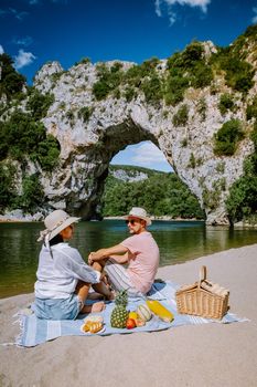 couple on the beach by the river in the Ardeche France Pont d Arc, Ardeche France,view of Narural arch in Vallon Pont D'arc in Ardeche canyon in France