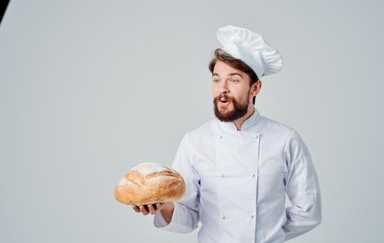 Happy cook in connected clothes holds a loaf of fresh bread in his hand