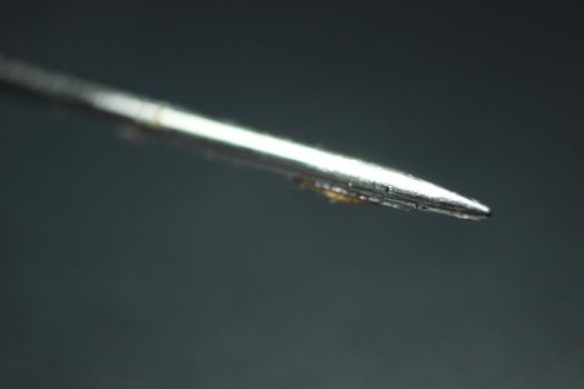 Macro photograph of sewing needle over the black background.