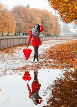 young girl with an umbrella stands on the alley of the park after the rain