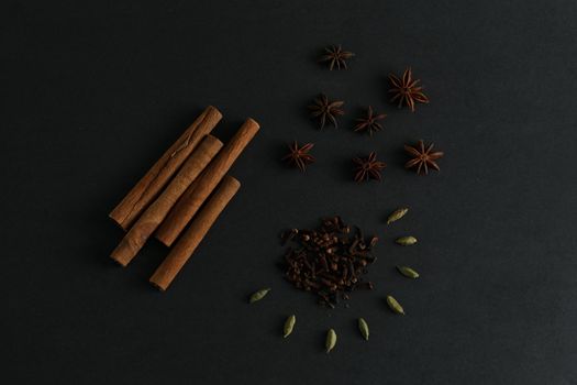 Cinnamon sticks, anise stars, clove and cardamon seed on black background flatlay