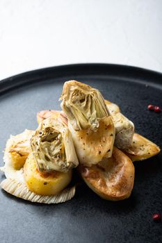 Baked potato and artichoke with fennel al forno, on white textured background