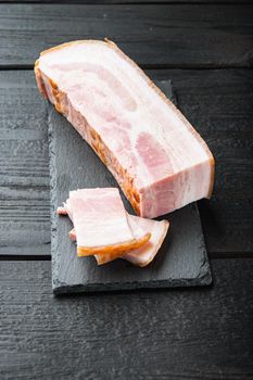 Smoked bacon, whole slab on black wooden table