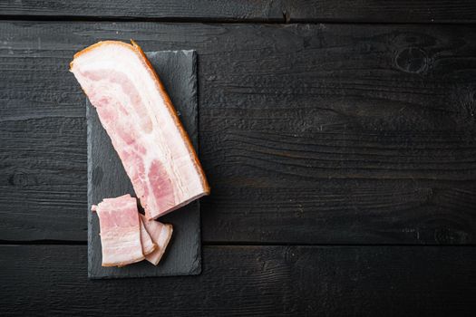 Smoked bacon, whole slab on black wooden table, top view with space for text