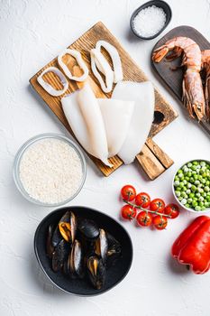 Raw ingredients for paella with seafood on white background, top view