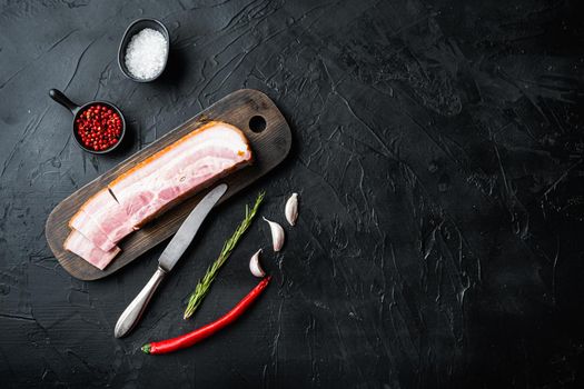 Smoked bacon, whole slab with herbs on black background, top view with space for text