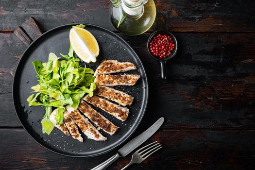 Crumbed chicken breast fillet grilled, on wooden table, flat lay with copy space