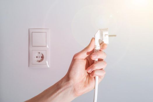 Energy concept: Plug, ready to connect. White cable and plug socket in the blurry background
