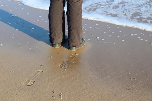 Human feet in black shoes at a baltic sea beach in northern Germany.