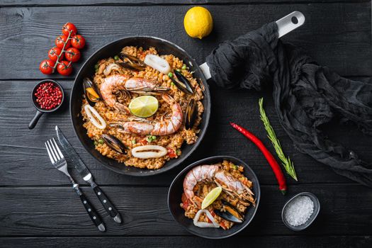 Paella on black wooden planks, top view
