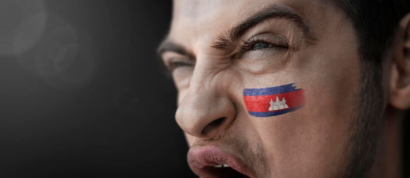 A screaming man with the image of the Cambodia national flag on his face