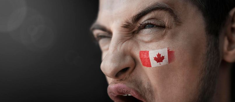 A screaming man with the image of the Canada national flag on his face