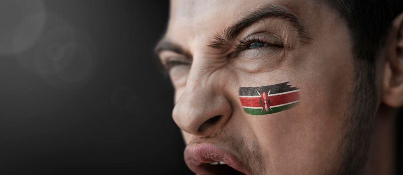 A screaming man with the image of the Kenya national flag on his face