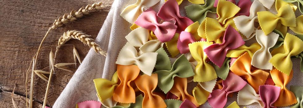 colourful background with raw food ingredients. Italian pasta farfalle with rye on rustic wooden background. Pasta recipes concept. Horizontal flat lay