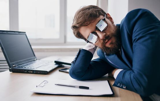 Business man sleeping at work wearing glasses with sheets of paper