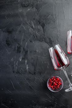 Red wine glass and pomegranate seeds, on black textured background with huge space for text, top view.