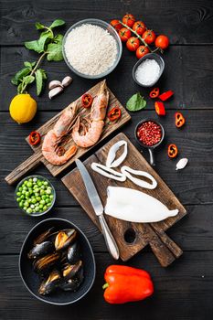 Raw paella ingredients on black wooden surface, top view
