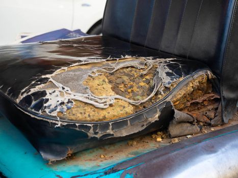 The moldy car seat is torn to see the foam inside the car seat.
