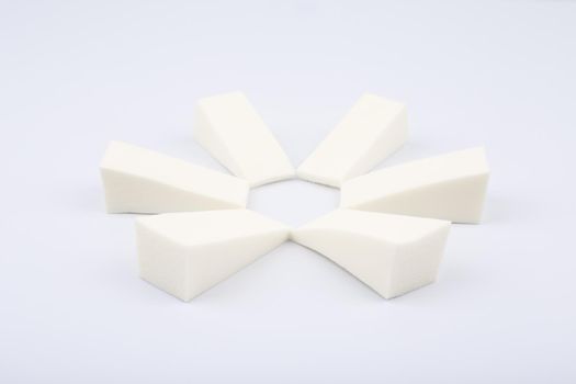 Triangle shaped make up sponges arranged in a circle on white background. Concept of visage and beauty blenders