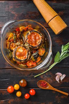 Portobello baked with cheddar cheese, cherry tomatoes and sage in glass pot on old wooden background top view.