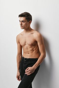 Sporty man with a naked torso on a light background and dark trousers model
