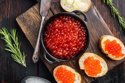 Canape toast with red caviar, on old dark wooden table background, top view flat lay