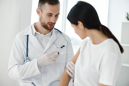 young doctor inject vaccine into patient's shoulder and syringe in hand with stethoscope laboratory