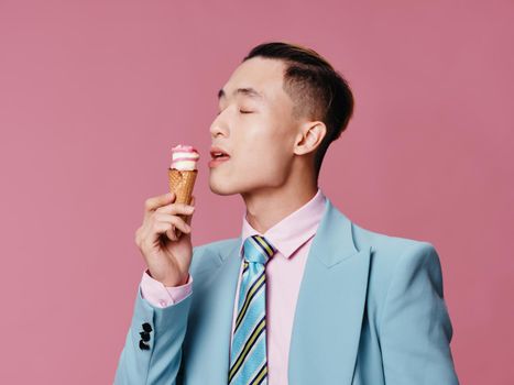 Cheerful man in blue suit ice cream enjoyment pink background