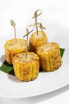 organic sweet corn on the cob vegan tapas snack food on white table background
