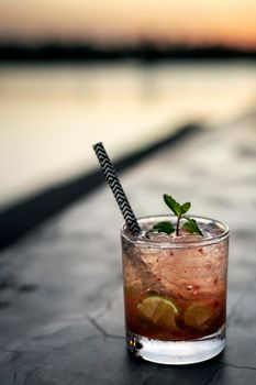 strawberry caipirinha mixed cocktail drink in outdoor bar at sunset