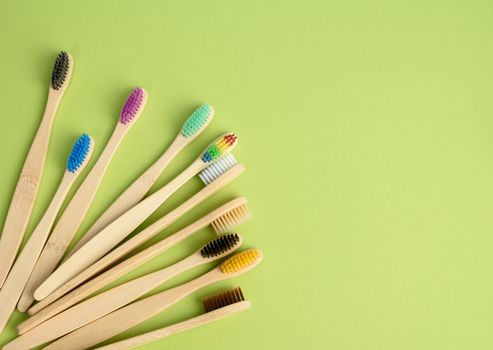 multicolored wooden toothbrushes on a blue background, plastic rejection concept