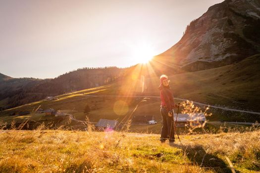 Hiking girl is enjoying the sundown in the mountains, sitting on the ground. Warm colors, alps, Austria