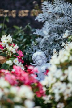 Remembrance concept: White angel on a grave, flowers