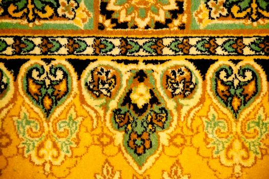 Fragment of an old Russian carpet. Crafted from a heavy, fleecy patterned fabric. View from the front. Brown with yellow.