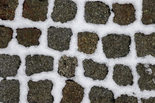 Surface of white snow on an old cobblestone way in winter.