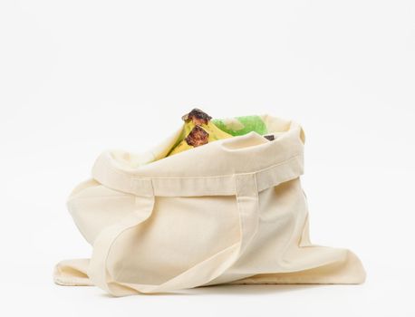 beige textile bag with fresh fruits on a white background