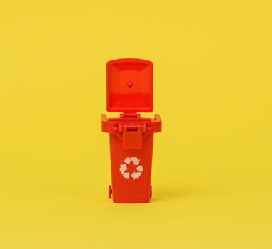 miniature of red plastic waste sorting bin on yellow background
