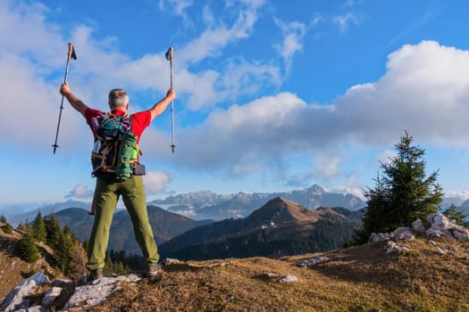 Hiker cheering elated and blissful with arms raised in the sky after hiking
