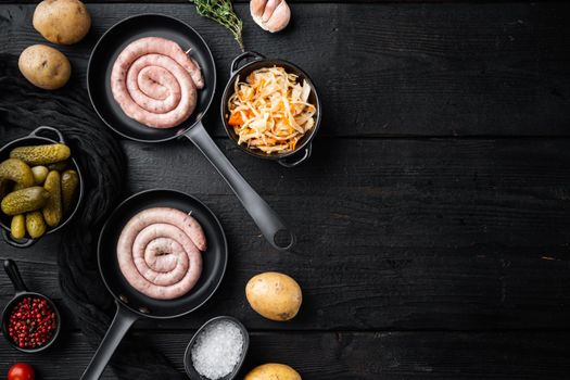 Roasted sausages with fermented cabbage in cast iron frying pan, on black wooden table background, top view flat lay , with space for text copyspace
