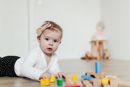 Little kid playing with colorful wooden building blocks. Blurred background