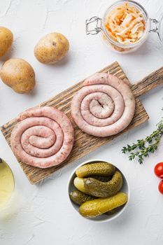 Wurst or Bratwurst with Fermented Cabbage, Pickled Cucumbers, and Spices, on white background, top view flat lay